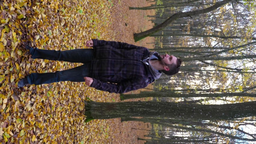 Young guy wearing a mask in the woods. Autumn, fallen leaves. Vertical video.