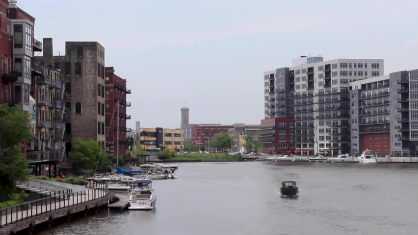 Boat driving down the Milwaukee river surrounded by residential and office buildings in Milwaukee, Wisconsin