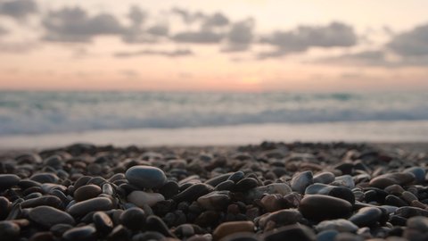 Close up of pebbles glistening on  beach at sunset with sea in background.