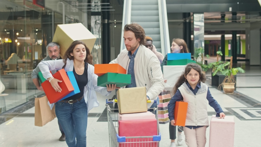 Group of Shopaholics With Shopping Bags Running Along Mall Hurrying to Make Purchases on Black Friday. Running to Be First In-Store. Crazy Shopping at Big Sales.