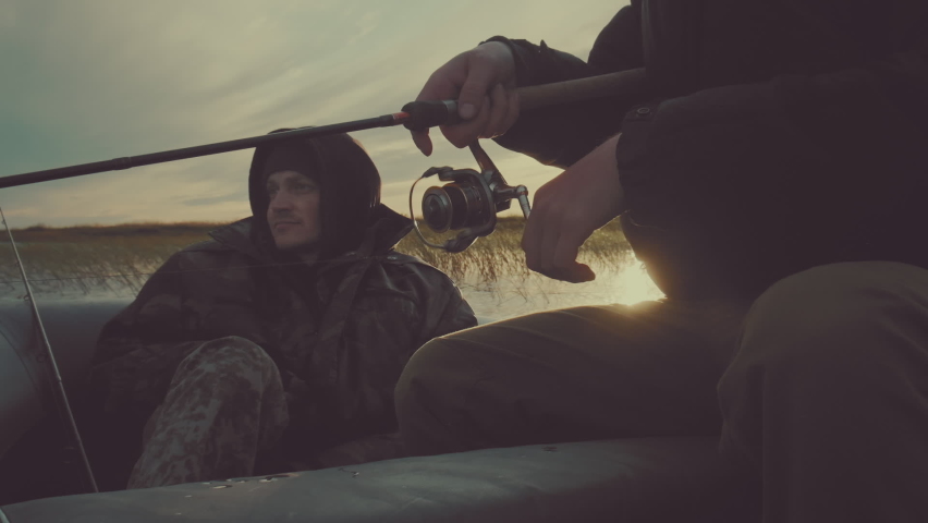 Friends fishing. Two friends fishing from the boat on the calm lake during sunset