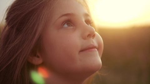 happy little girl child closed her eyes dreams. kid wants a dream come true portrait at sunset. baby daughter silhouette dreaming of a happy childhood. free face sister lifestyle side view thinks
