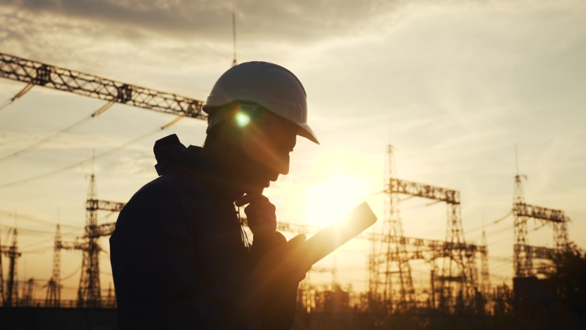 electrical silhouette worker engineer a working with digital tablet, near tower with electricity power. energy business technology industry concept. electrical studying reading documents on tablet Royalty-Free Stock Footage #1061849734