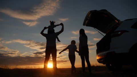 happy family children kid together standing next to car watching the sunset silhouette in park. family travel dream concept. happy family stand with sunlight their backs journey watching in the park