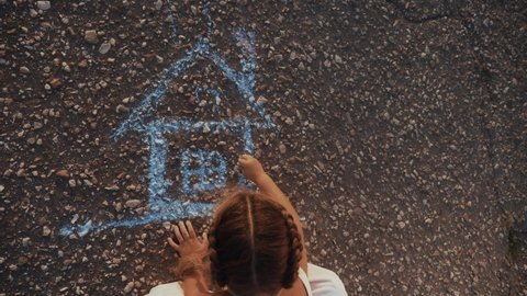 child kid draw a house on the asphalt with chalk . childhood mortgage dream kid concept. little girl playing draws with chalk big house. concept home loan mortgage for a dream residential building