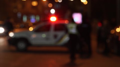 Police car with flashing lights, blurred frame. Silhouettes of people and cars. Background