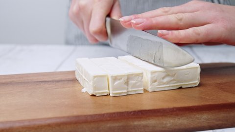 Close-up of Cutting/slicing cubes of feta cheese on a board for a Greek Salad.