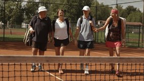 Senior, retiree people go playing tennis on sunny day, talking, smiling and having fun on the tennis court outdoor. Middle shot in slow motion. Sport and active lifestyle of senior people. - Powered by Shutterstock - Get 15% off with code: PIKWIZARD15