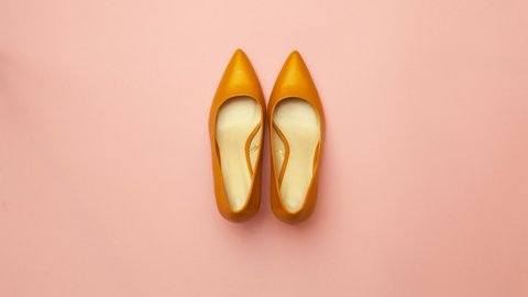 Yellow shoes with heels move on a pink background. Stop motion video.