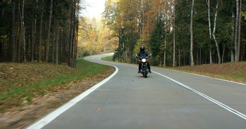 WIDE TRACKING Biker riding his custom built vintage retro motorcycle on a scenic forest road. Shot on RED cinema camera with 2x Anamorphic lens