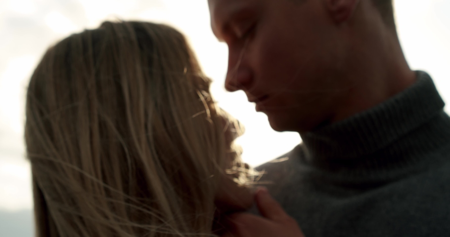 Kissing wedding couple stands against the sunset on a beach in Iceland. Close up Slow motion