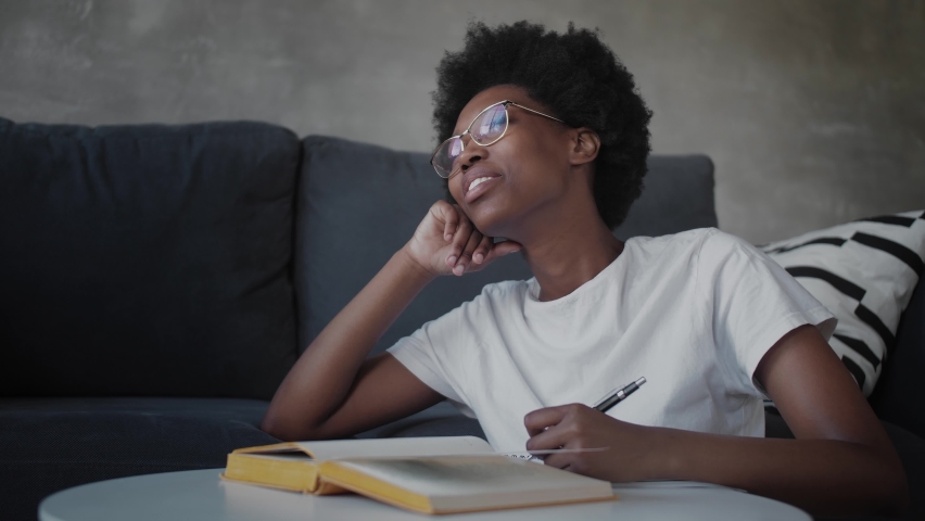 African American girl writes in a notebook in a cozy room Royalty-Free Stock Footage #1061863147