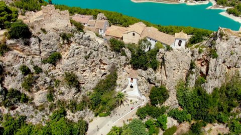 Beautiful Mediterranean village in the province of Alicante (Spain). A small medieval village between rocks. Nearby Benidorm. Drone views. Reservoir at the bottom of the valley. Third plane.