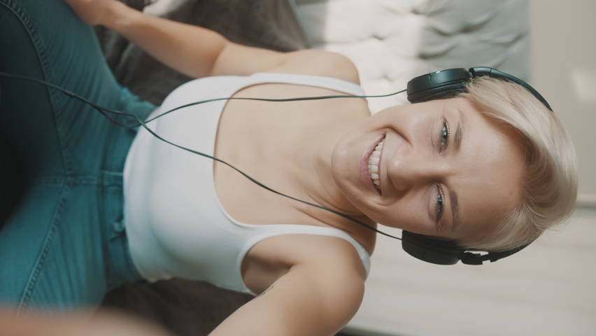 Vertical shot European blonde answering a video call vertical