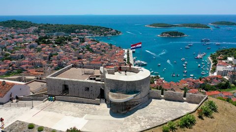 Croatia flag on the tower of an ancient fortress with view to the town of Hvar waterfront aerial view, Dalmatia archipelago of Croatia
