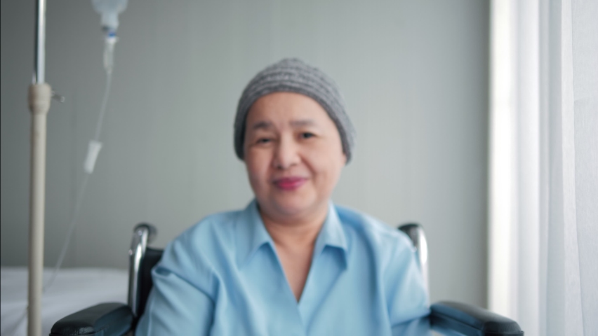 Portrait of smiling elderly Asian woman sitting on wheelchair with cancer wearing look at camera, elderly people healthcare concept. Royalty-Free Stock Footage #1061869489