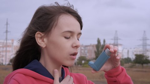 The girl is choking with asthma. Young girl with asthma attack in outdoor.