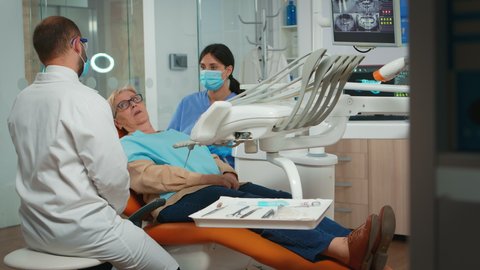 Dentistry doctor doing hygienic cleaning of teeth using sterile dental tools. Patient lying with open mouth in stomatological office, stomatologist performing examination in modern clinic.