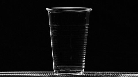 Melting plastic cup on black background. Plastic pollution or high temperature concepts
