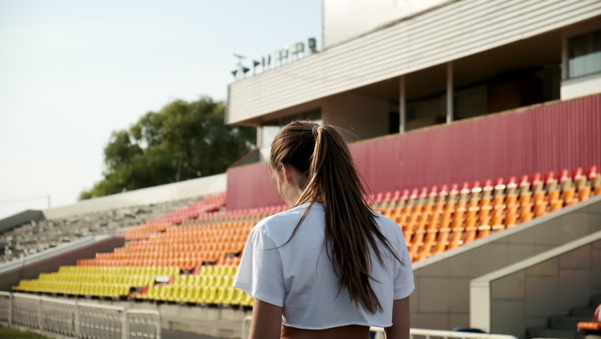 Follow-up shot of slim young fitness runner in sportswear running on stadium track. fit sportive pretty female in activewear jogging, shot from behind. sports, healthy lifestyle. woman runs, back view
