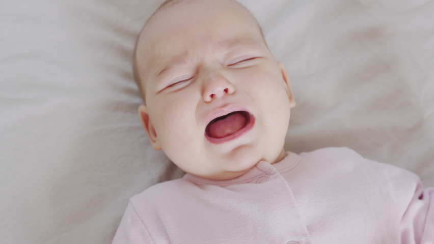 A Baby in Lies on the Bed and Cries. Child is Upset and Crying. Royalty-Free Stock Footage #1061884639