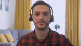 Portrait of young man with wireless headset talking with customer on video call