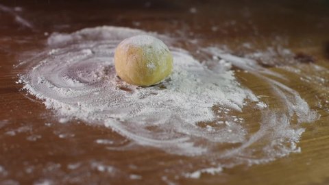 Cook rolls the dough with a rolling pin, shaping the dough. Female hands kneading dough in flour on the table. Close up. Production of cake. Bakery products.