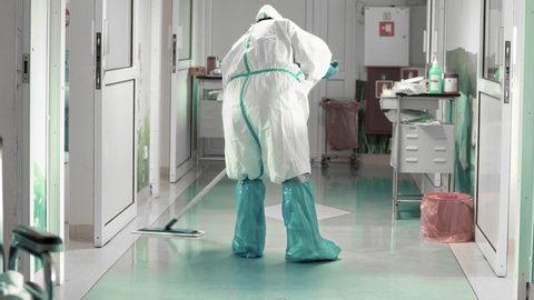 Cleaning the hospital floor in full protective clothing, difficult working conditions during an epidemic