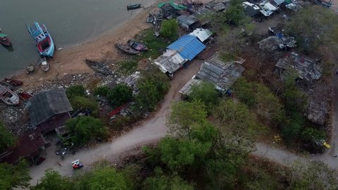 Overhead shot of motorbike and sidecar driving around Thai fishermen's shacks