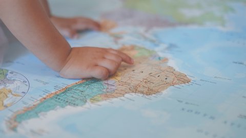 4k video of the right hand of a little girl on a colorful map of America pointing at Brazil and then it moves up to point at the USA