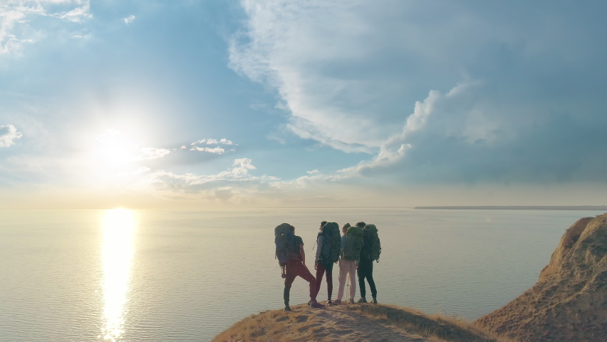 The four tourists standing on the mountain cliff against the beautiful seascape