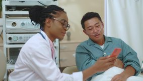 Joyful couple of asian patient and female therapist watching online videos on smartphone having fun communicating together. Healthcare. Assistance. Doctor. Hospital. Technology.