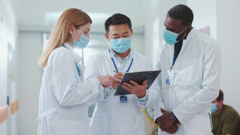 Business team of healthcare multi-ethnic workers wearing face masks discussing coronavirus outbreak virus infection pandemic negotiating in the hospital. Quarantine.