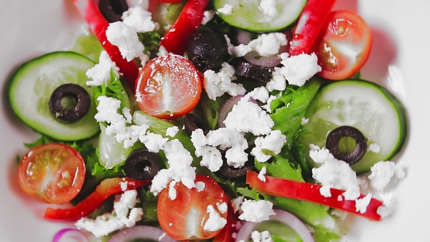 Greek salad on a white plate rotates in a circle