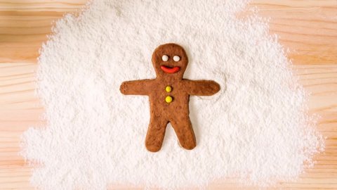 Stop motion animation of a gingerbread man making snow angel on flour.