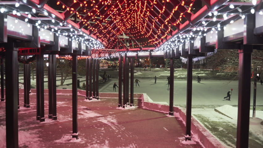 Outdoor ice skating under Christmas lights at Olympic plaza in Downtown Calgary Alberta Canada.