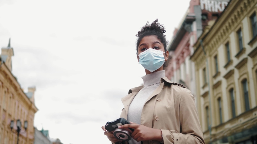 Gorgeous dark skinned black young woman with Afro hairstyle wearing protective mask against COVID virus, afrrican american girl with medical mask, public space post covid, safe travel after pandemic | Shutterstock HD Video #1061923000