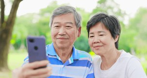slow motion of Asian elderly couple have video chat by mobile phone happily outdoor