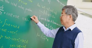 slow motion of asian senior male calculus professor is writing and pointing in front of blackboard in the classroom at college