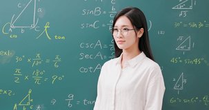 slow motion of asian senior high school female math teacher smile to you - standing in front of blackboard at classroom