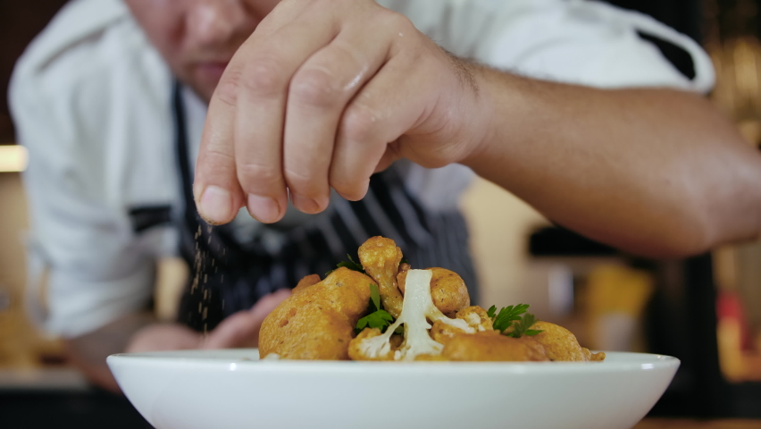 Close-up Professional Chef at Restaurant Kitchen Serves Dish Adding Final Ingredient by Hand. Cooking Vegetarian Food at Modern Home Cuisine. Delicious Fish and Chips. Preparing Meal Kitchen Slow mo Royalty-Free Stock Footage #1061926687