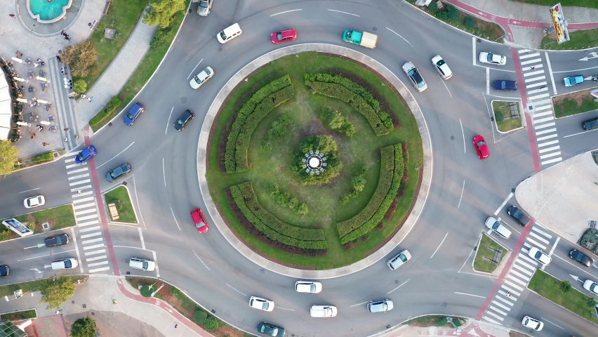 Vehicles on a busy roundabout junction. Traffic circle with a lot of cars. Top down aerial view on a circular intersection in Podgorica Montenegro. Royalty-Free Stock Footage #1061930266