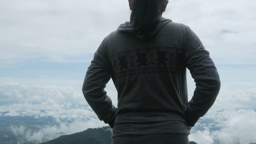 Rear view of Asian young woman enjoying with foggy nature on peak mountain in the morning.