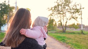 Front view, a young beautiful girl in a medical black mask with a small child in her arms looks at a beautiful sunset. - Powered by Shutterstock - Get 15% off with code: PIKWIZARD15