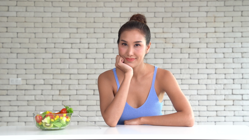 Asian woman in joyful postures with hand holding salad bowl