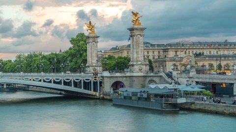 Bridge of Alexandre III spanning the river Seine timelapse. Decorated with ornate Art Nouveau lamps and sculptures. View from Invalides bridge. Paris. France. Blue cloudy sky before sunset