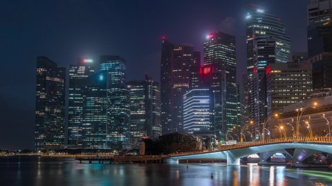 Esplanade bridge and downtown core skyscrapers in the background Singapore night to day transition timelapse. Illuminated towers reflected in water
