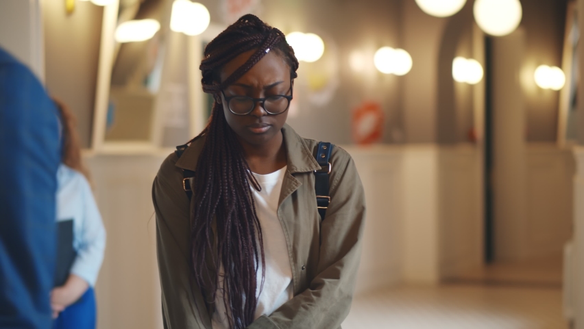 Depressed afro-american female student walking in college corridor. Portrait of stressed young college female failed exam and feeling worried and anxious having problems in university | Shutterstock HD Video #1061948023