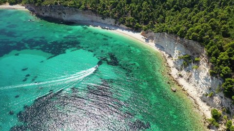 Aerial drone video of tropical paradise exotic island covered in pine trees with turquoise crystal clear beach in Caribbean destination