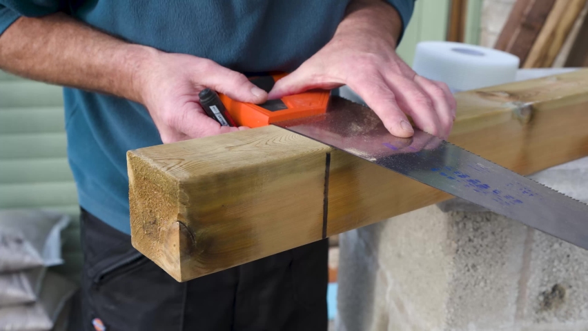 Close up of male using a hand saw to mark out hand rail post ready to be cut. home improvments, garden work